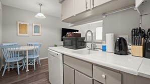 A modern kitchen with white cabinets, a white countertop, and a dining area with blue chairs. - Modern Central Austin Retreat Near UT & Downtown (Austin)