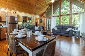 A wooden cabin interior with a dining area, kitchen, and living room. - 1.5 Miles to Dollywood & Pigeon Forge attractions, 2 bd/2 bath, gated community. (Sevierville)