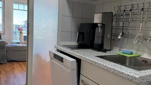 A compact kitchen with a dishwasher, a coffee maker, and a sink. - Dat Stürboord with North Sea view, swimming pool and sauna (Wurster Nordseeküste)