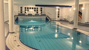 An indoor swimming pool with a tiled floor and a central staircase leading to a viewing platform. - Dat Stürboord with North Sea view, swimming pool and sauna (Wurster Nordseeküste)