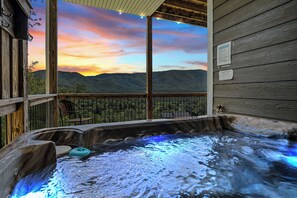 Un jacuzzi con vistas a montañas y al atardecer.