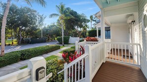 A covered porch with a wooden deck, white railings, and a mailbox. - Duck Key Townhome on open Water (Duck Key)