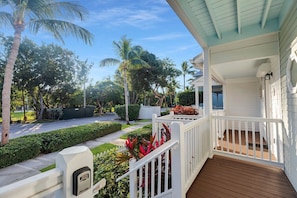 A covered porch with a wooden deck, white railings, and a mailbox. - Duck Key Townhome on open Water (Duck Key)