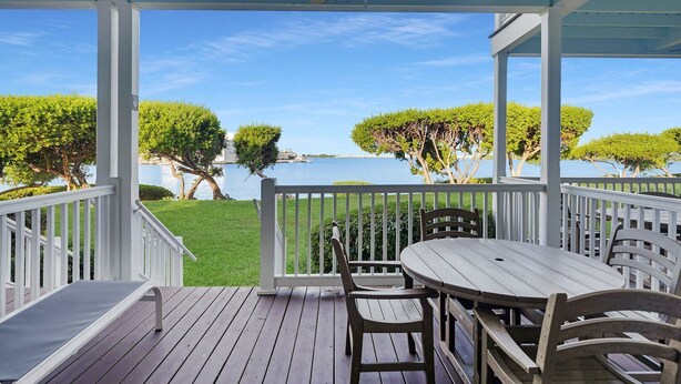 A covered outdoor area with a table and chairs, a ceiling fan, and a view of the water and trees. - Duck Key Townhome on open Water (Duck Key)
