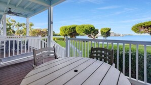 A covered outdoor deck with a table and chairs, overlooking a body of water and greenery. - Duck Key Townhome on open Water (Duck Key)