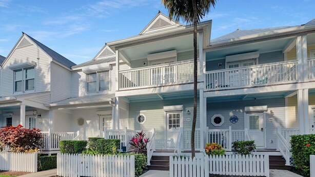 A two-story residential building with a balcony, a porch, and a white picket fence. - Duck Key Townhome on open Water (Duck Key)