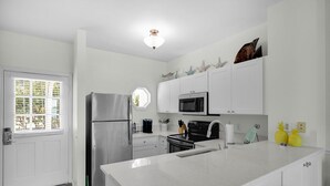 A modern kitchen with white cabinetry, stainless steel appliances, and a large island. - Duck Key Townhome on open Water (Duck Key)