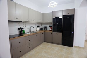 Eine moderne Küche mit beigen Schränken, einer Edelstahl-Spüle und einem schwarzen Kühlschrank.