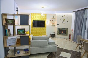 A living room with a sofa, TV, fireplace, and a bookshelf. - Koko's Apartment (Rethymno)