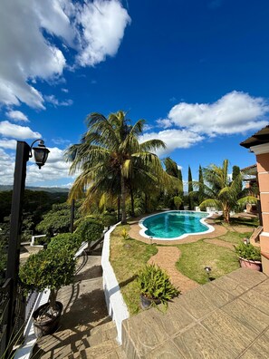 Ein Swimmingpool, umgeben von Palmen und wolkenlosem, blauem Himmel.