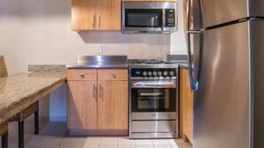 A kitchen with wooden cabinets, a microwave, a stove, and a refrigerator. - Last minute deal on Aruba Resort;Large 1st Floor Suite;Sleeps 4; 1 MasterBedroom (Oranjestad)