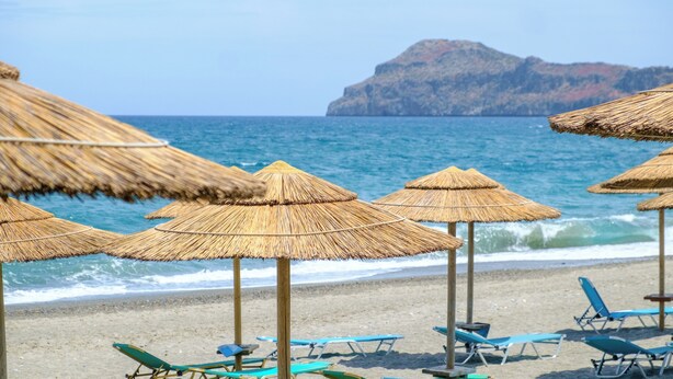 Ein Strand mit Strohdächern und Liegestühlen.