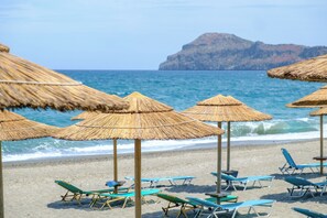Ein Strand mit Strohdächern und Liegestühlen.