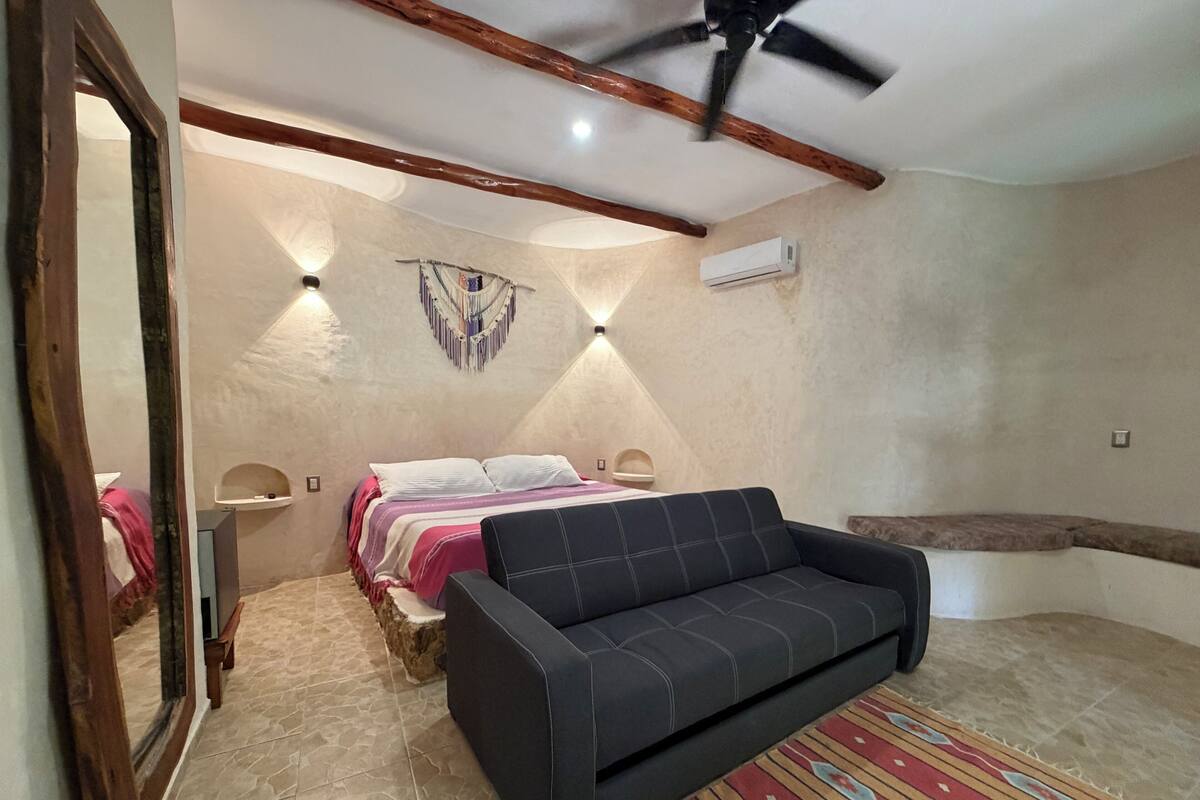 Un dormitorio con cama, sofá, ventilador de techo y aire acondicionado.