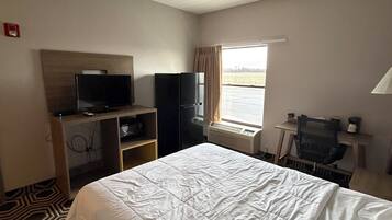 A hotel room with a bed, a television, a desk, and a window with curtains.