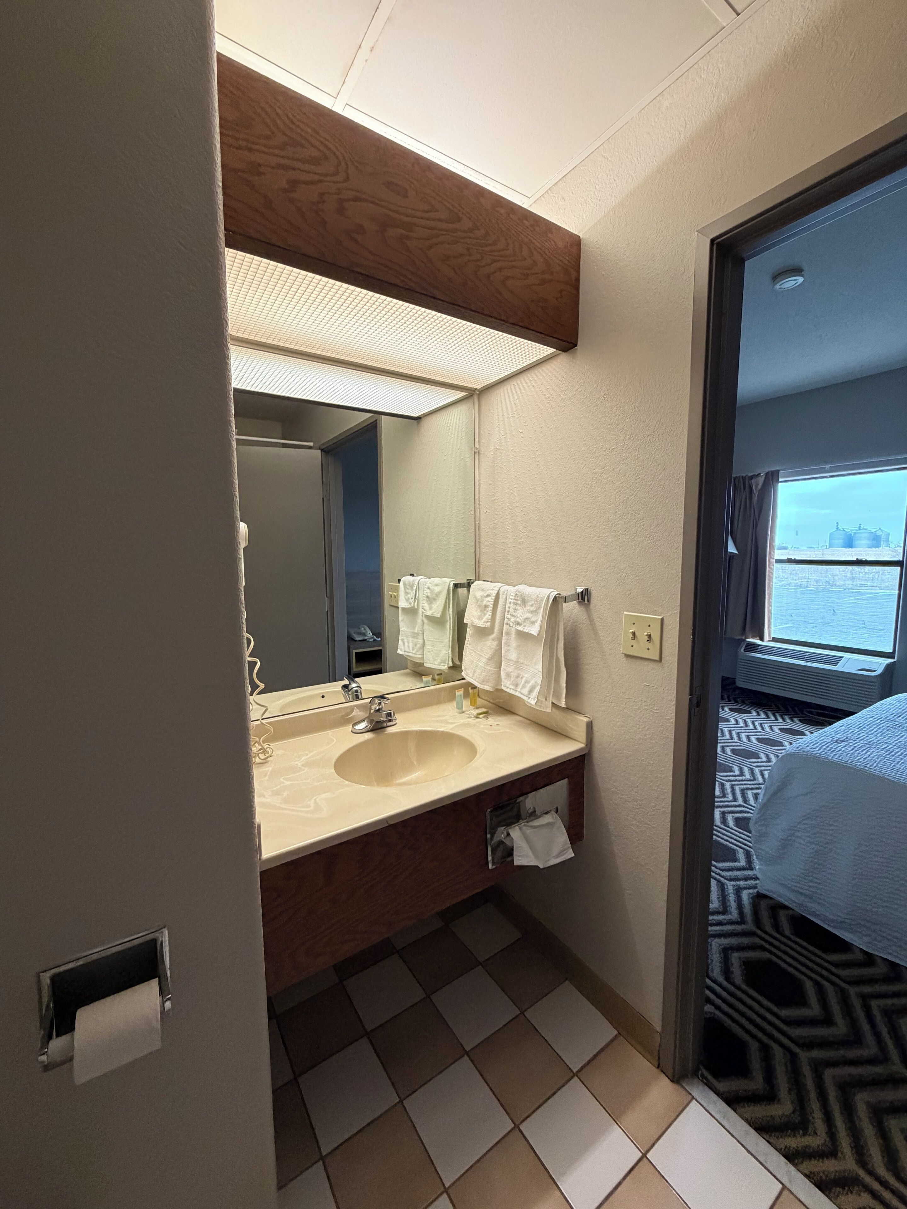 A hotel bathroom with a sink, mirror, and towels.