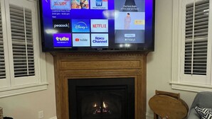 A flat-screen TV mounted above a fireplace, displaying various streaming services.