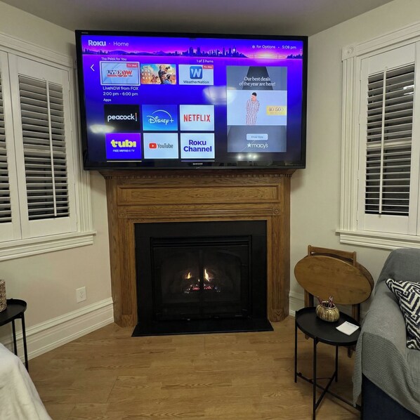 A flat-screen TV mounted above a fireplace, displaying various streaming services.