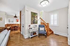 A spacious living area with a wooden staircase, a dining table, and a comfortable seating area.
