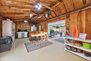 A rustic wooden interior with a kitchen, dining area, and a small outdoor seating space.