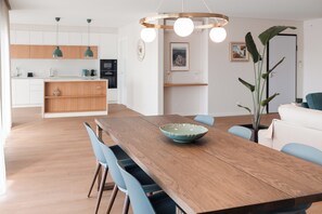 A modern kitchen with wooden cabinets, a central island, and pendant lighting. - Magnificent 2-bedr. apartment in downtown Olhão, fully equipped with private parking. (Olhão)