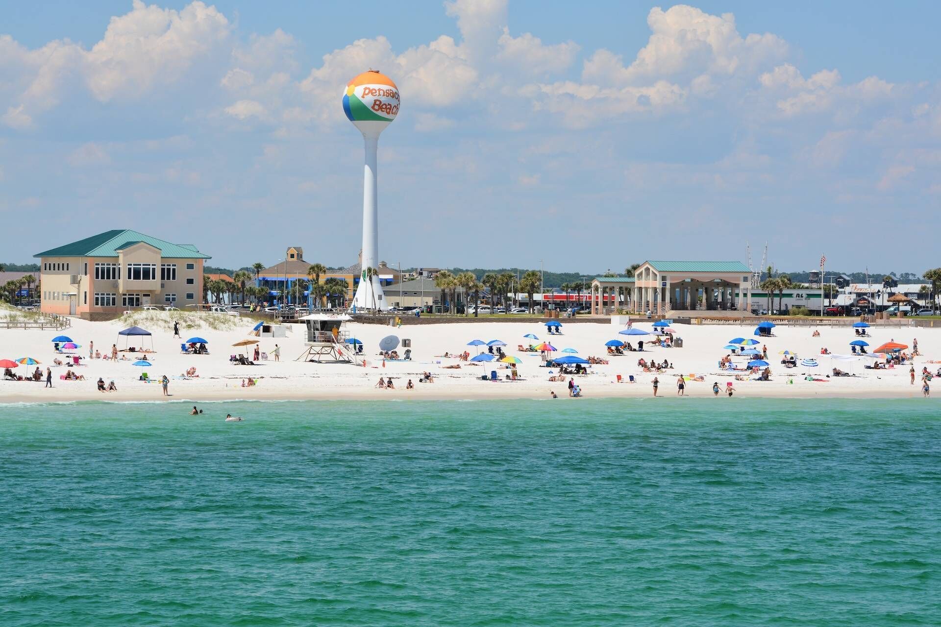 A beach with a water tower, beach umbrellas, and a lifeguard tower.