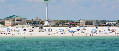 A beach with a water tower, beach umbrellas, and a lifeguard tower.