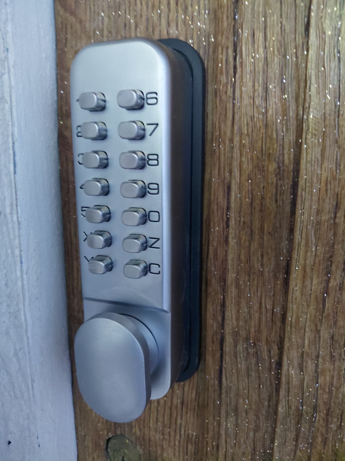 Uma fechadura de porta com teclado numérico e um orifício para chave.