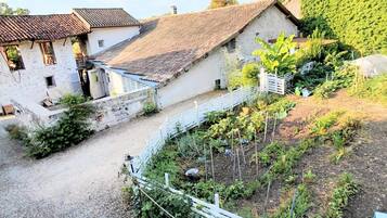 Una proprietà rurale con edifici in pietra, un vialetto sterrato e un'area giardino recintata.