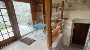 A wooden interior with a stone wall, a blue table, and a door leading to a balcony. - Chalet-style self-contained cottage in quiet countryside (Voiron)