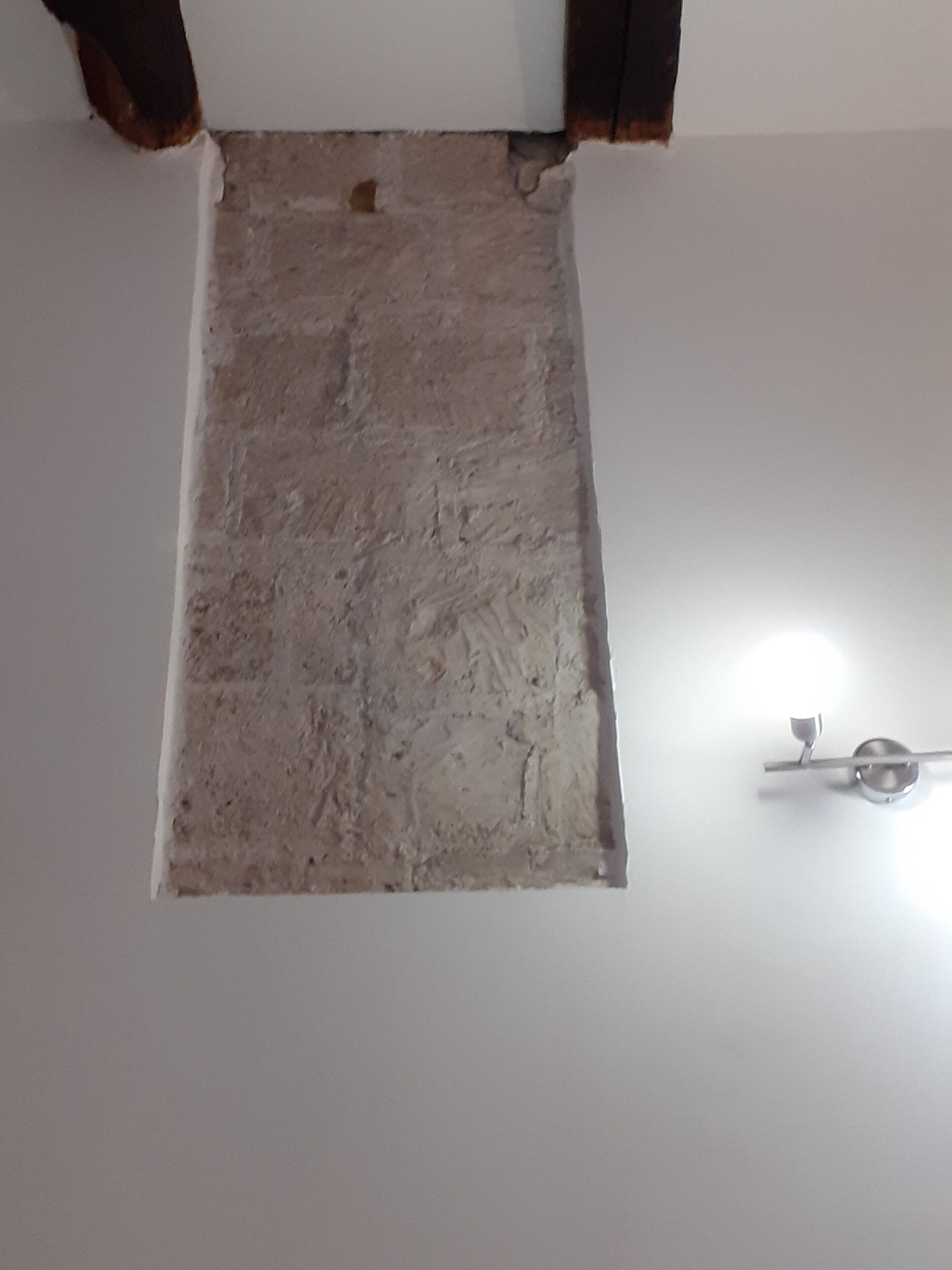 Une pièce avec un sol blanc et une partie du mur présentant une texture particulière.