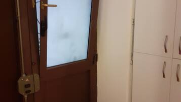 Una porta in legno con un pannello di vetro satinato, una parete bianca e un armadio bianco con due ante e due cassetti.