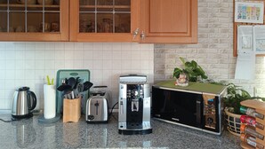 A kitchen with wooden cabinets, a stainless steel kettle, a toaster, a coffee maker, and a microwave.