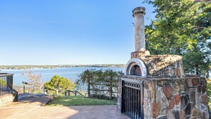 Un edificio de piedra con chimenea, una verja y vistas a un cuerpo de agua.