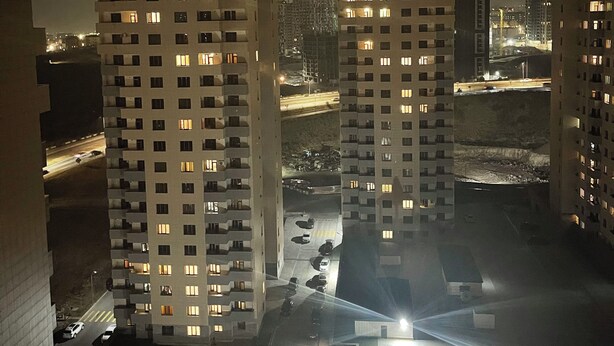 A nighttime view of high-rise residential buildings with illuminated windows, a road with vehicles, and a playground with a slide. - Cozy 2-bedroom apartment in pleasant Yerevan with AC (Yerevan)