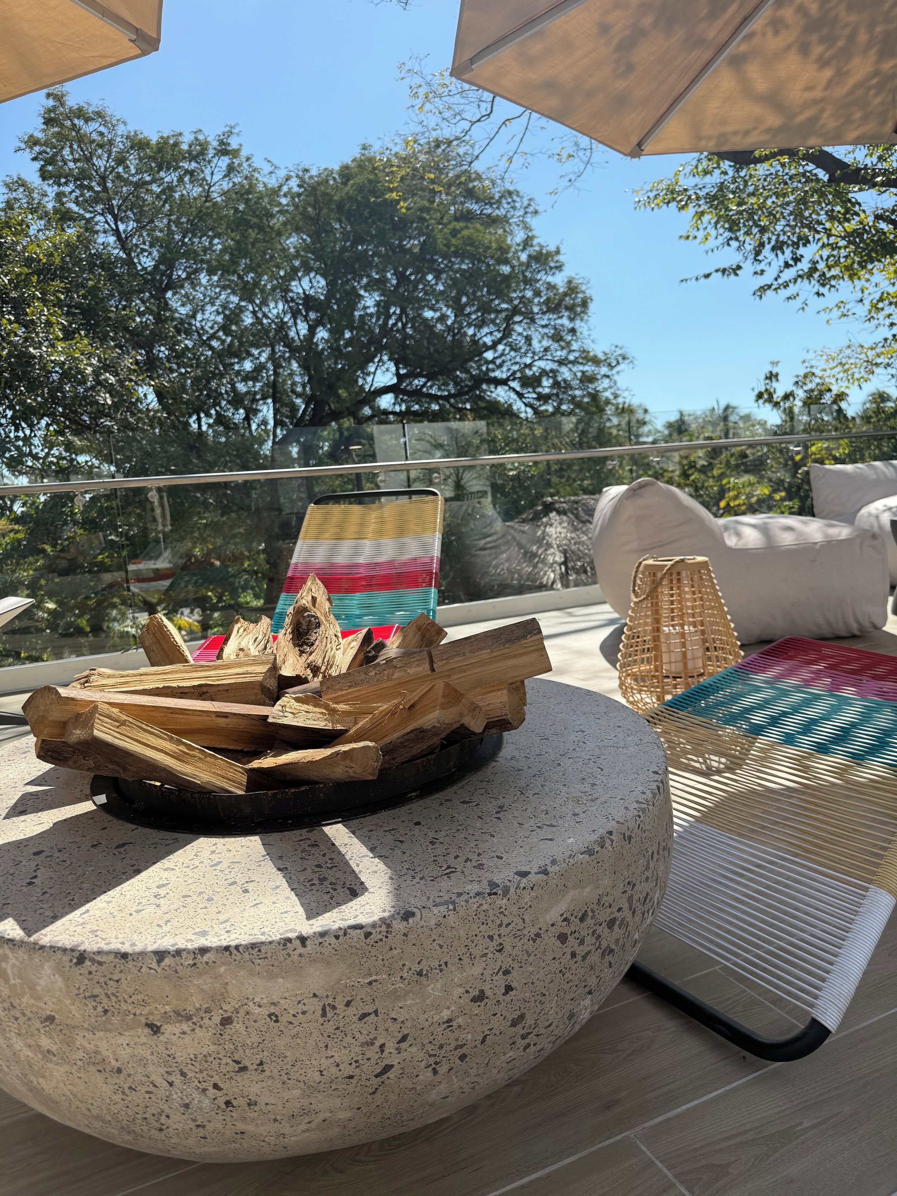 Un patio con una chimenea, sillones de descanso y vistas a árboles.