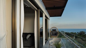 Ein Balkon mit Meerblick, einer Couch, einem Sessel und einem Tisch mit einer Pflanze.