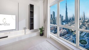 Una sala de estar moderna con un amplio ventanal que ofrece vistas a la ciudad, un televisor de pantalla plana y un diseño minimalista.