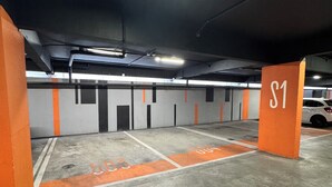 Un parking souterrain avec des piliers orange, un sol en béton et des places de stationnement délimitées.