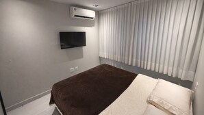 Une chambre à coucher avec un lit, un téléviseur fixé au mur et un appareil de climatisation.