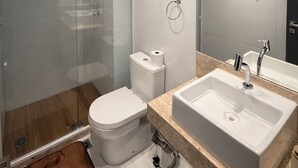 Une salle de bain moderne avec une douche à parois de verre, des toilettes, un lavabo et un grand miroir.