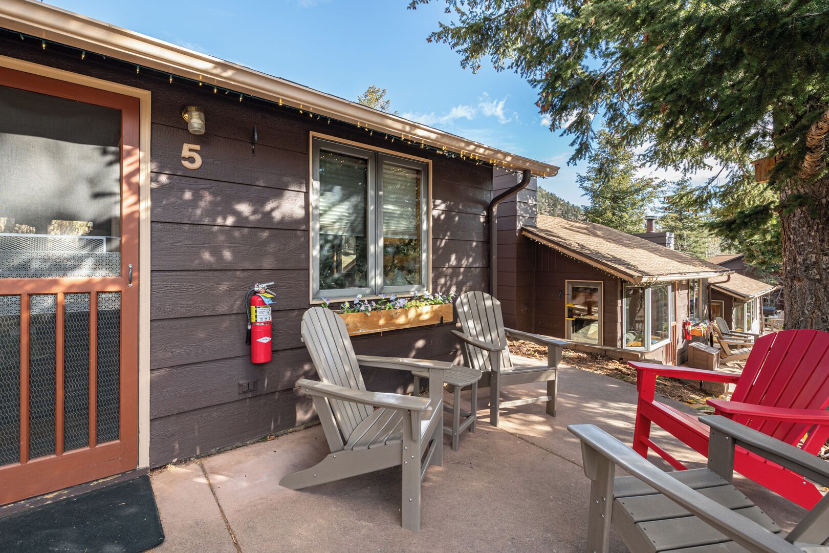 A cabin with a number 5 sign, outdoor seating, and a fire extinguisher.
