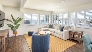 Ett modernt vardagsrum med en soffa, två fåtöljer, ett soffbord, en tv och en takfläkt.