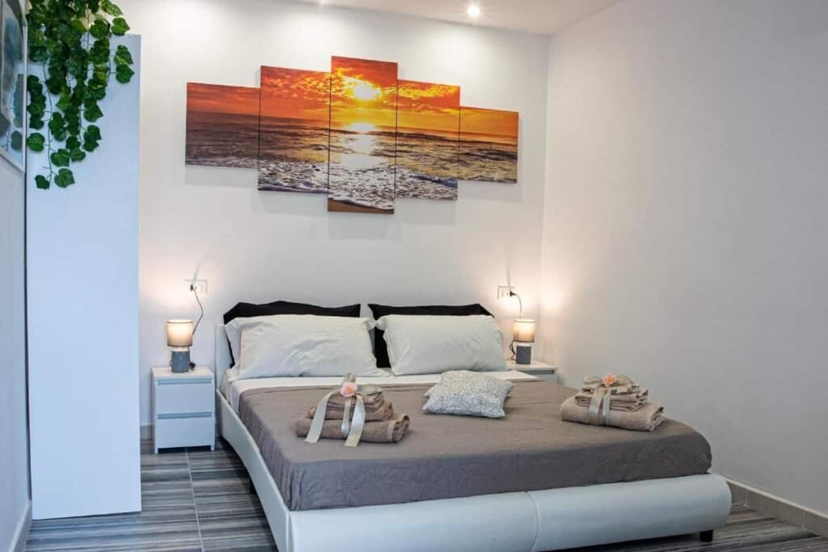 Una camera da letto moderna con un letto, comodini e un'opera d'arte appesa al muro.