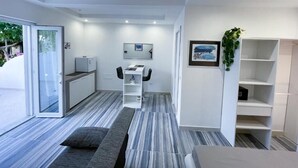 Moderni huone, jossa on sänky, työpöytä ja tuoli. Huoneesta on liukuovi, joka johtaa ulkotilaan.
