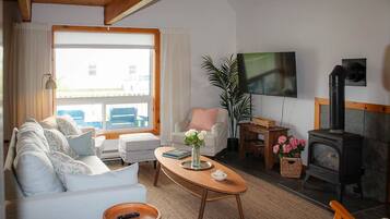 A cozy living room with a sofa, armchairs, a coffee table, a fireplace, and a television.