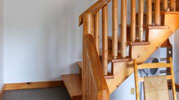 Una scala in legno con ringhiera, gradini rivestiti di tappeto e una decorazione ad ancora fissata al muro.