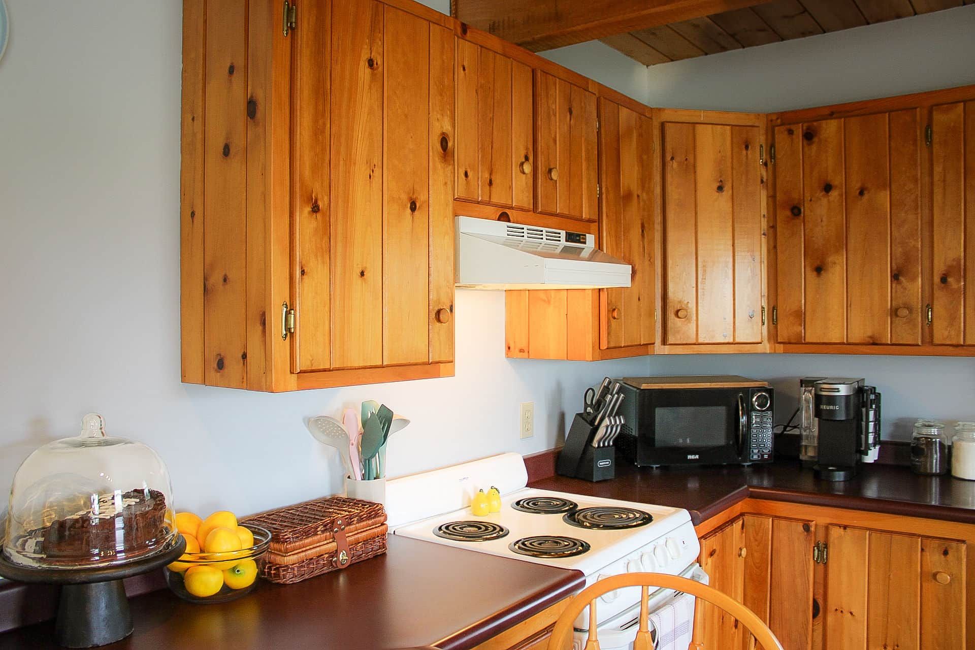Una cocina con armarios de madera, estufa, microondas y cafetera.