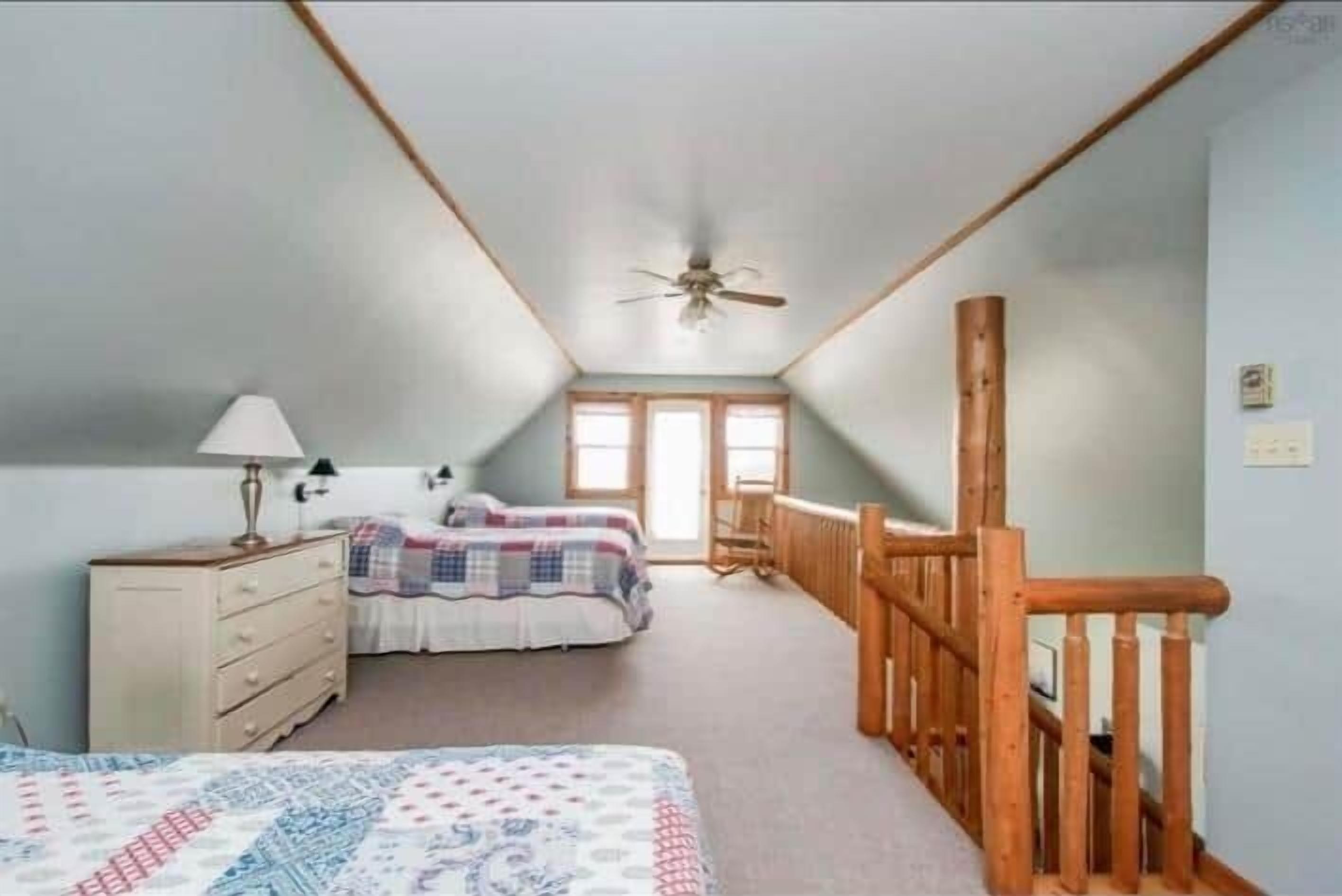 Une chambre à coucher avec un lit, une commode et une rambarde en bois le long du mur.