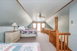 A bedroom with a bed, dresser, and a wooden railing along the wall. - Ocean-View Chalet · King + 2 Queens · Pet-Friendly (Lockeport)